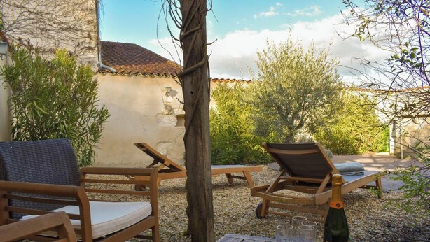 An outdoor seating area with wooden furniture and a bottle of champagne. - Saint Privat House: Pool, Family & Greenery (Saint Privat en Périgord)