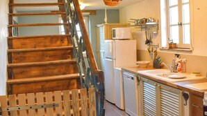 A wooden staircase leading to a kitchen with a clock, a refrigerator, and a sink. - Saint Privat House: Pool, Family & Greenery (Saint Privat en Périgord)