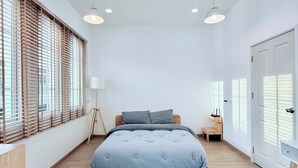 A modern bedroom with a large bed, wooden floor, and a grey rug. - Minimalist Townhome Stay (Pattaya)