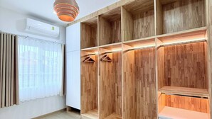 A modern room with a wooden wardrobe, a ceiling fan, and a window with curtains. - Minimalist Townhome Stay (Pattaya)