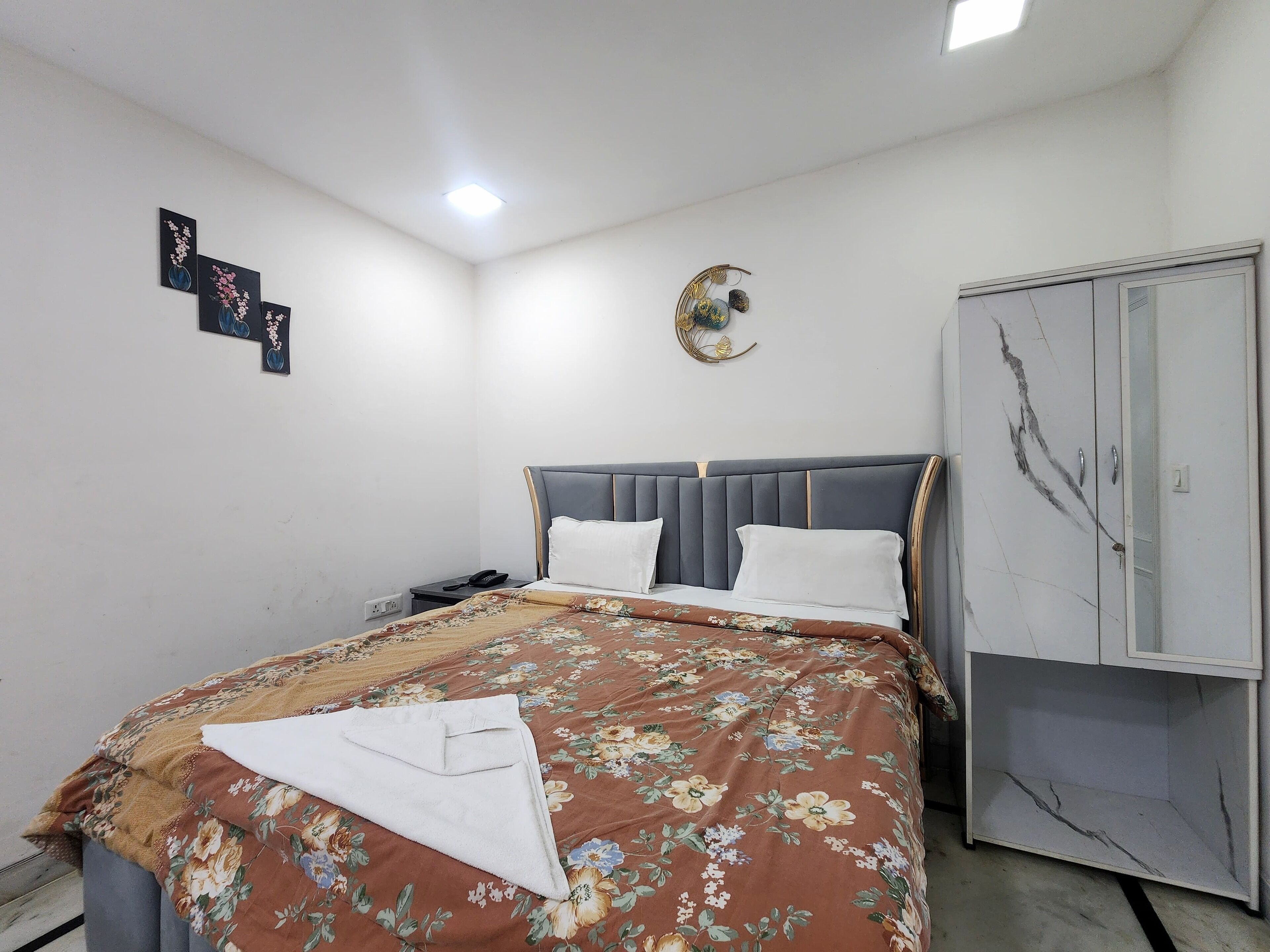 A bedroom with a bed, a wardrobe, and a wall-mounted light fixture.