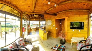 A wooden cabin with a dining area, a bar, and a TV. - Pousada Morada da Serra (Cambara do Sul)