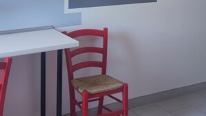 Una habitación moderna con una mesa blanca, una silla roja y un reloj de pared grande.