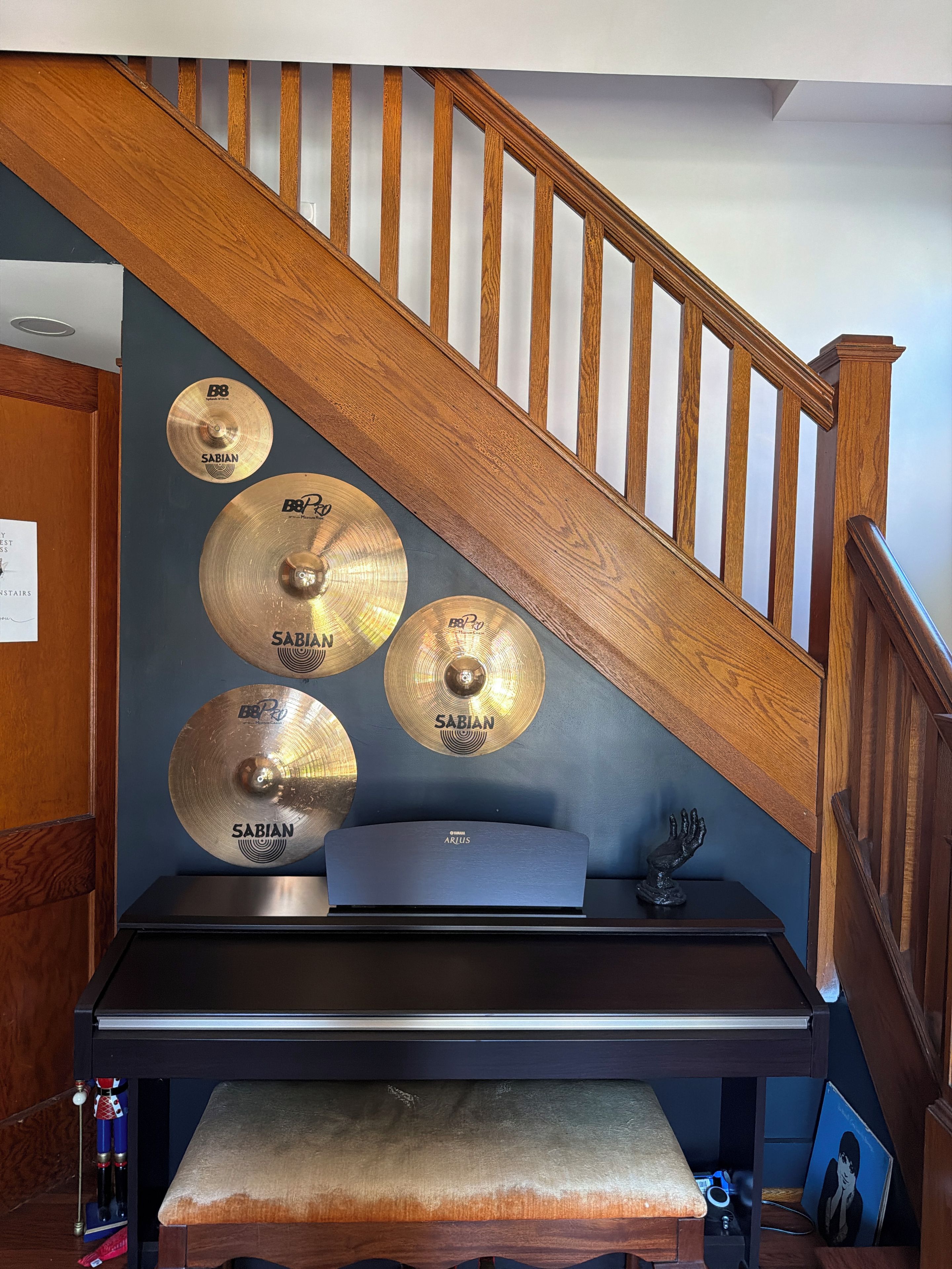 A staircase with wooden railings and a wall-mounted drum set with Sabian cymbals.