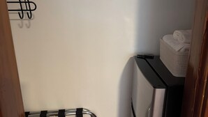 Una cocina compacta con un refrigerador de acero inoxidable, una cesta blanca pequeña y un tendedero de metal.
