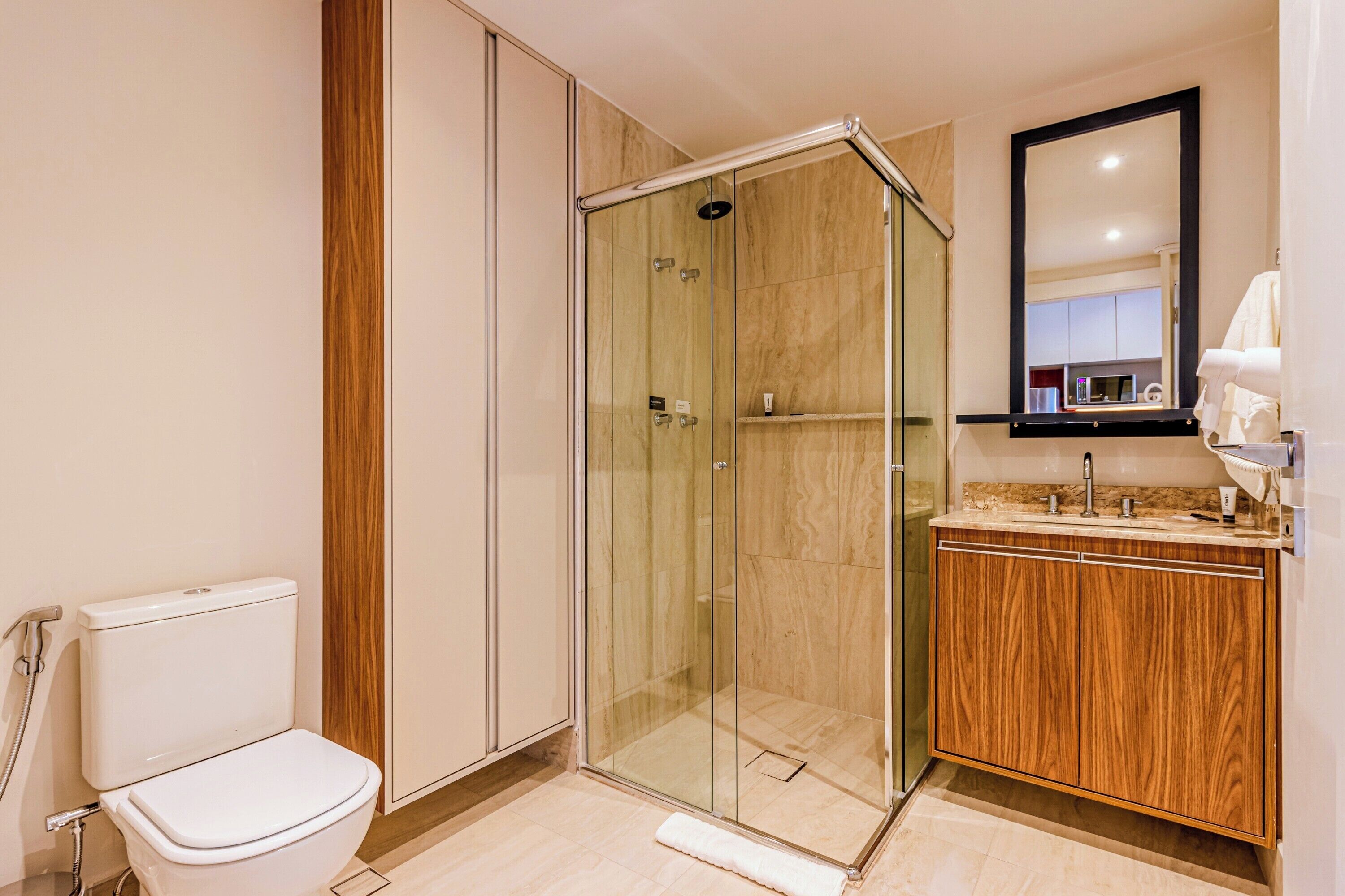 A modern bathroom with a glass-enclosed shower, a wooden vanity, and a toilet.