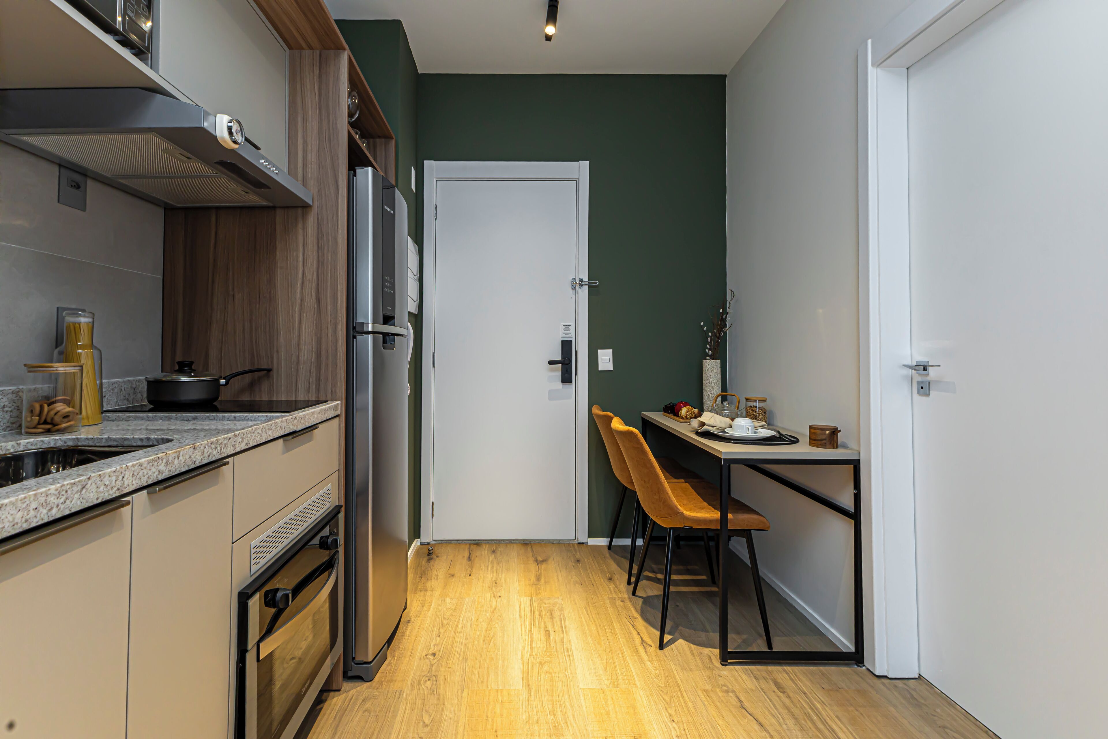 A compact kitchen with a microwave, stove, and oven. There is a dining area with a table and chairs.
