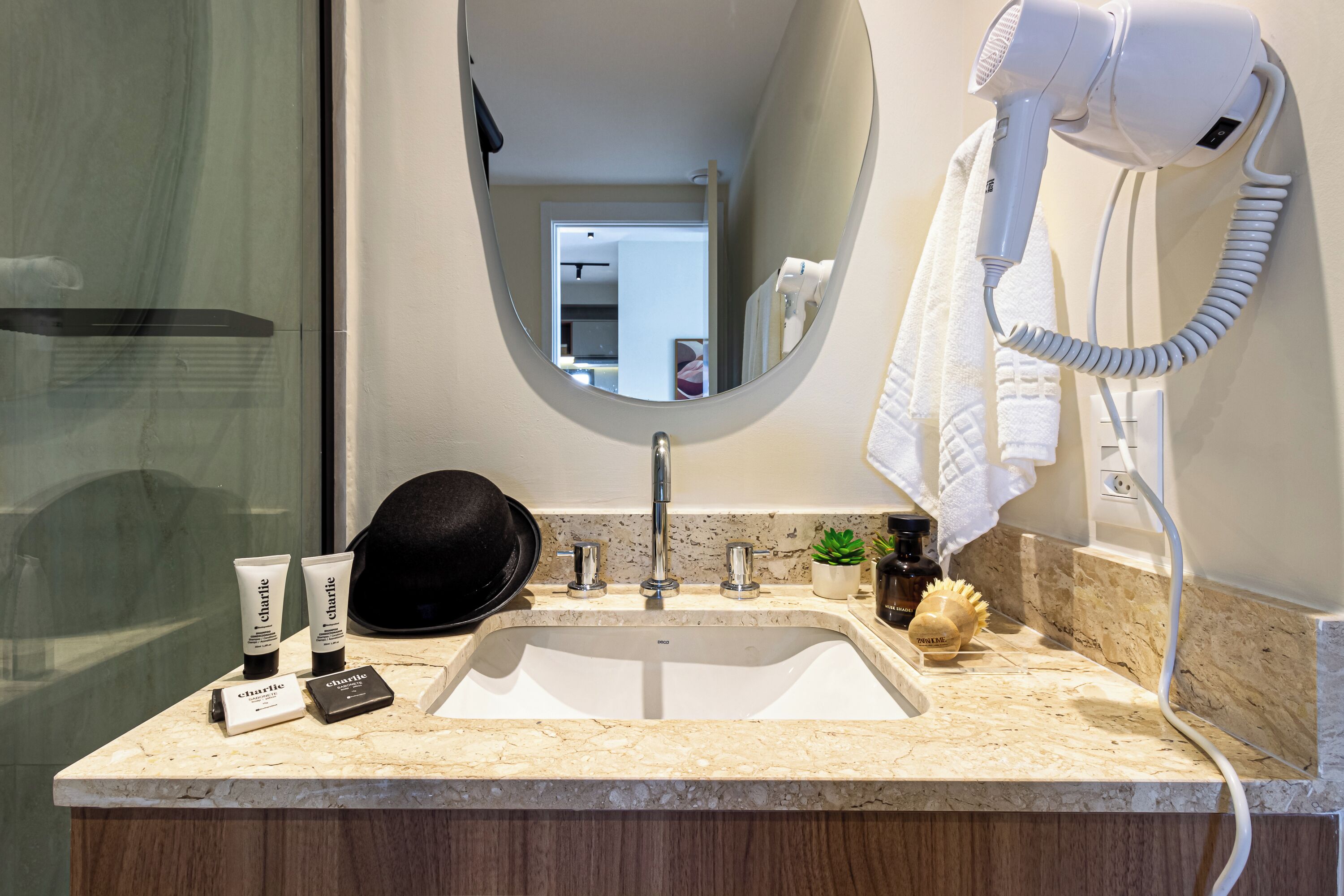A bathroom with a sink, mirror, hairdryer, and toiletries.