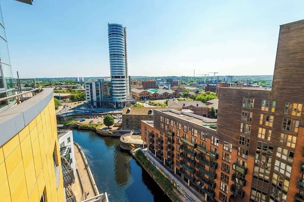 A high-rise building with a curved facade, a river running through the city, and adjacent residential buildings.