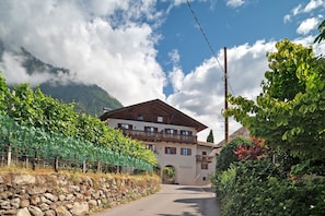 A mountain lodge with a stone wall, a wooden balcony, and a clear sky.