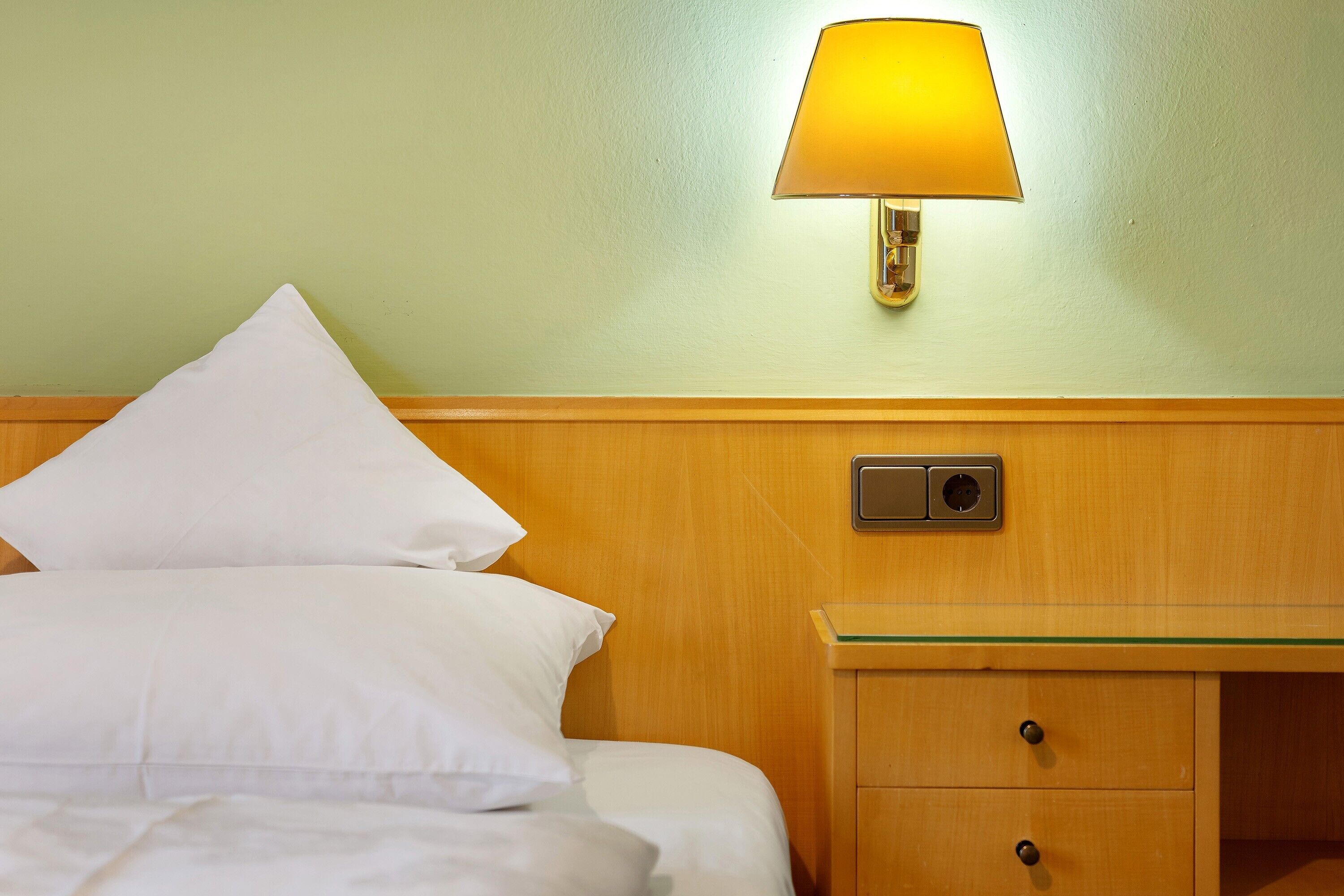 Une chambre d’hôtel avec un lit, une table de chevet, une lampe et un tiroir.