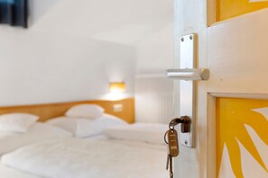 Une chambre d’hôtel avec un lit, un lecteur de carte d’accès fixé au mur et une porte ornée d’un motif jaune.