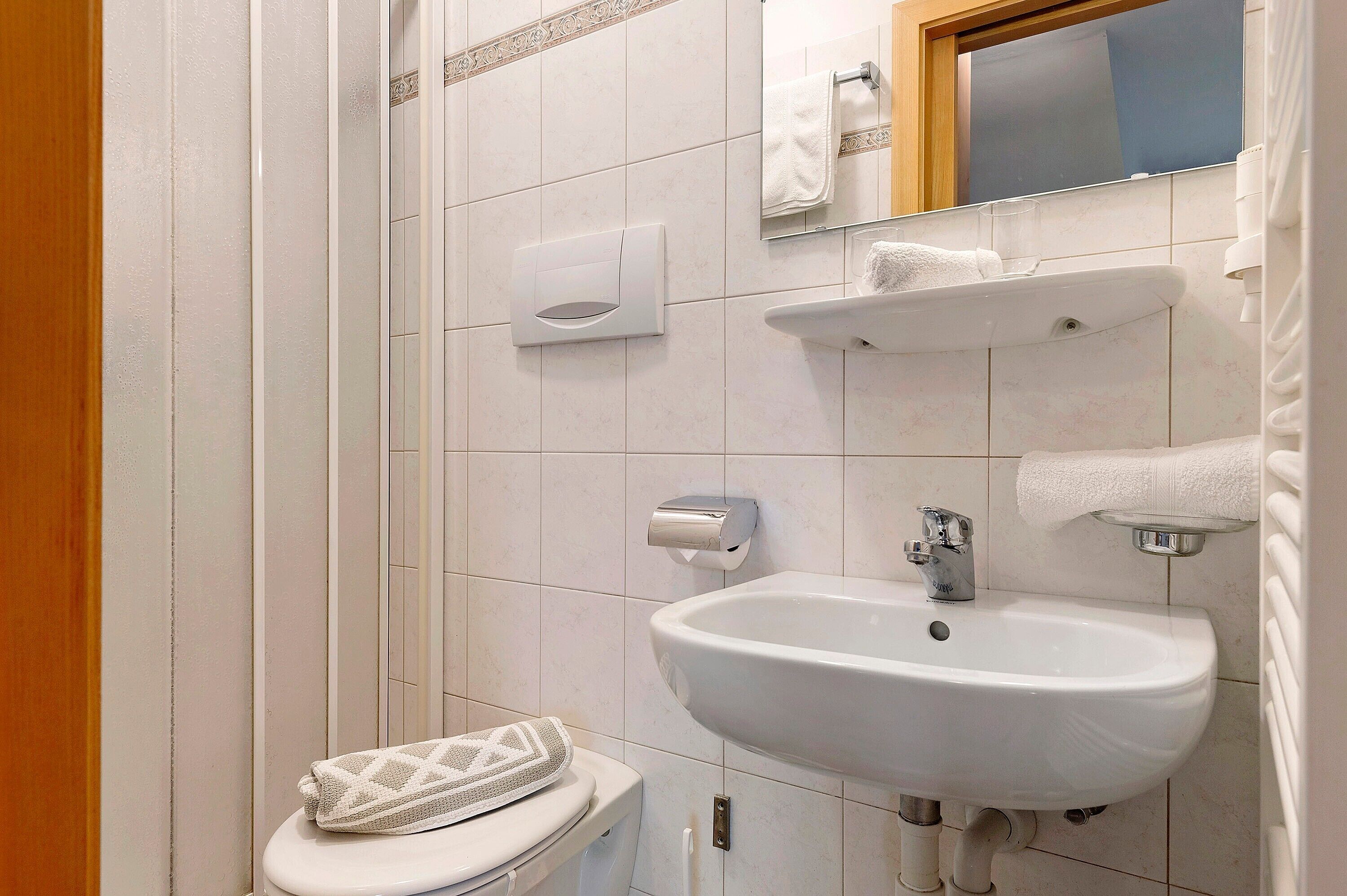 Une salle de bain équipée de toilettes, d’un lavabo, d’un distributeur de serviettes et d’un miroir.