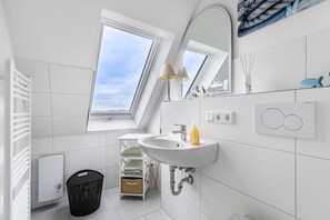 Un baño moderno con tragaluz, un lavabo blanco y un perchero para toallas.