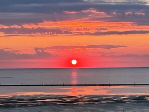Un atardecer sobre un mar tranquilo con un muelle que se adentra en el agua.