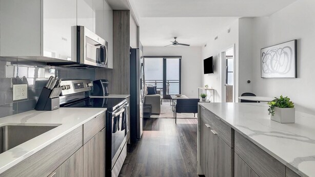 Een moderne keuken met een centraal eiland, geïntegreerde apparatuur en uitzicht op de woonkamer.