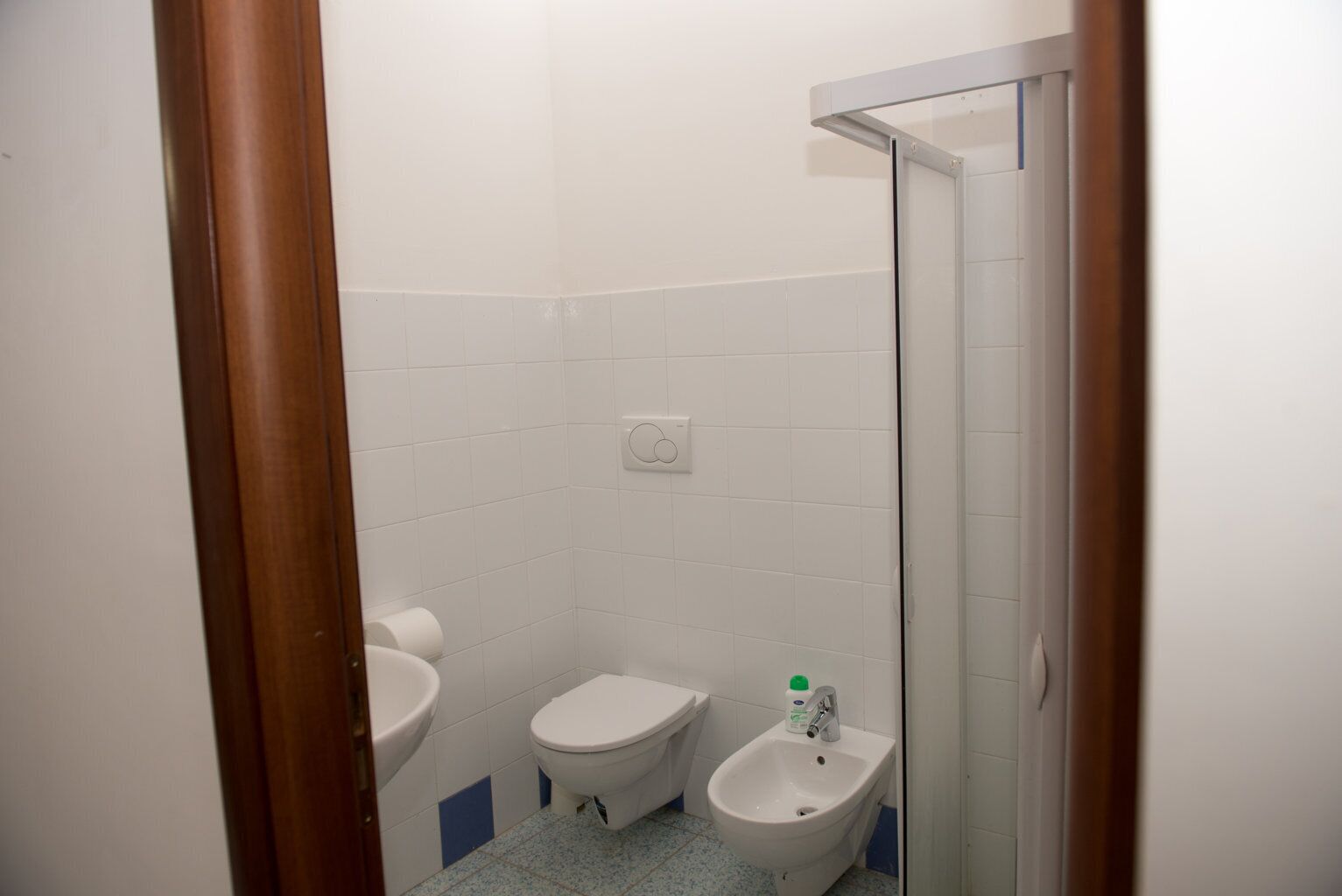 A small, clean bathroom with a toilet, bidet, and sink.