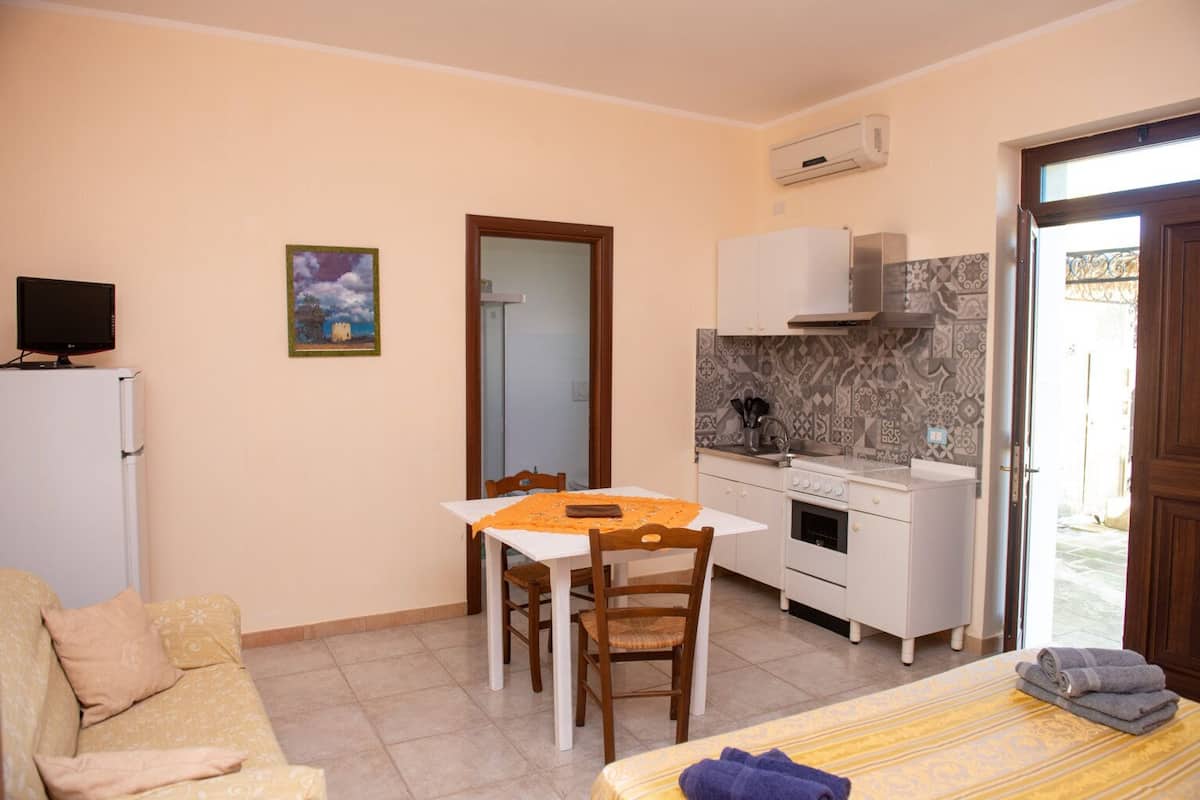 Un espacio habitable compacto con kitchenette, comedor, sofá y cama.