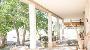 A covered outdoor area with columns, potted plants, and a stone bench. - Villa dei Bruno (San Donato di Lecce)