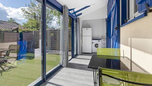 A modern kitchen with a washing machine, a dining area with a table and chairs, and a sliding glass door leading to a backyard. - Holiday Home in Carcans – Terrace, Air Conditioning, Near Lake (Carcans Maubuisson)