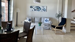 A modern living room with a sofa, two armchairs, a coffee table, and a dining area with chairs and a glass table. - Villa Over the 5th Green (San Bartolomé de Tirajana)