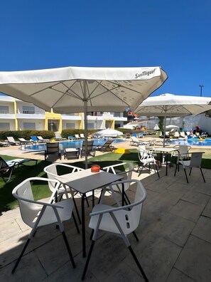 A poolside area with outdoor seating, umbrellas, and a pool.