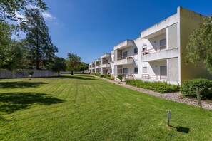 Een rij moderne, meerlaags gebouwen met balkons, een verzorgd gazon en een helderblauwe lucht.