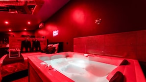 A red-lit room with a large bathtub, a wooden cabinet, and a neon sign.