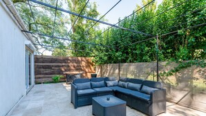 An outdoor patio with a sectional sofa, a small table, and a pergola.