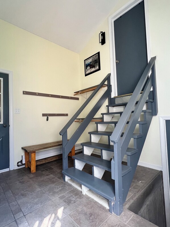 A staircase with blue railings and wooden steps, a bench, and a door with a dark frame.