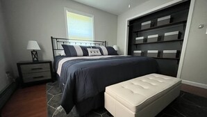 A bedroom with a bed, bedside table, lamp, and a built-in closet.