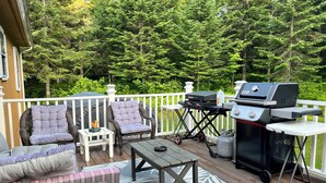 A deck with wicker furniture, a grill, and a table.