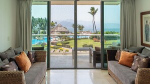 A spacious room with a large sliding glass door leading to a pool area, furnished with two sofas and a dining table.