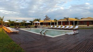 A poolside area with lounge chairs, umbrellas, and a stone building in the background. - Casa Río Spa (San José)