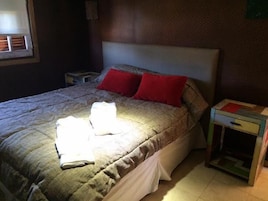 Quarto com cama, mesa de cabeceira e janela.