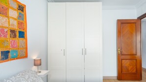 A bedroom with a bed, a wardrobe, a door, and a wall-mounted artwork. - Brigth Apartment 'Macarena' with Balcony, Wi-Fi and Air Conditioning (Sevilla)