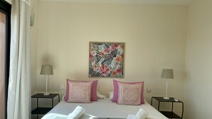 Hotelkamer met een bed, twee nachtkastjes, twee lampen, een bloemenbedekking en een schilderij met een zebra thema aan de muur.