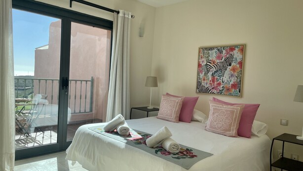 Een hotelkamer met een bed, een balkon en een schilderij aan de muur.