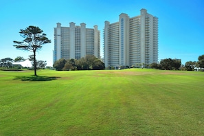 Un grand hôtel moderne composé de plusieurs immeubles de grande hauteur, doté d’une pelouse bien entretenue et agrémenté de quelques arbres.