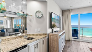 A modern kitchen with granite countertops, a built-in dishwasher, and a large window overlooking the ocean.