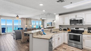 A modern kitchen with a large island, stainless steel appliances, and a view of the ocean.