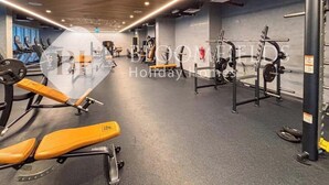 Ein Fitnessstudio mit Trainingsgeräten, darunter Laufbänder, Kraftgeräte und Bänke.