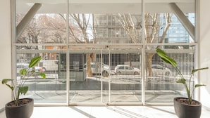 A view through a large window with metal bars, potted plants, and a parking lot with cars. - Nicaragua Hollywood Suites & Lofts by Argenhost (Buenos Aires)