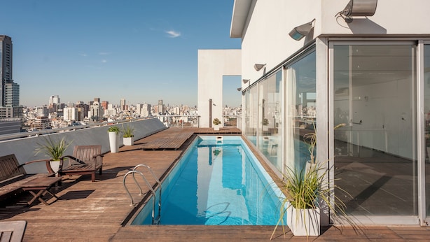 A rooftop pool with wooden deck seating and potted plants, overlooking a city skyline. - Nicaragua Hollywood Suites & Lofts by Argenhost (Buenos Aires)