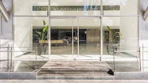 A modern hotel entrance with a glass facade, a reception desk, and potted plants. - Nicaragua Hollywood Suites & Lofts by Argenhost (Buenos Aires)
