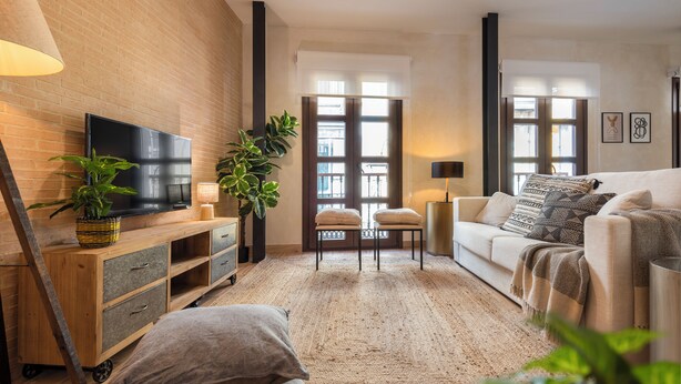 A modern living room with a flat-screen TV, wooden furniture, a large plant, and a cozy sofa. - MH Apartments Central Sevilla (Seville)