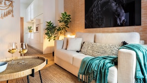 A modern living room with a white sofa, a large horse mural on the wall, a round coffee table, and a teal throw blanket. - MH Apartments Central Sevilla (Seville)