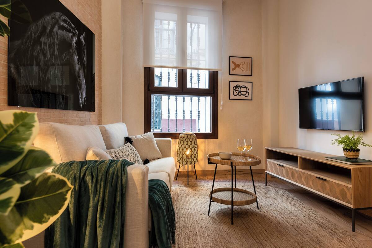 A modern living room with a sofa, a coffee table, a TV, and a large window.