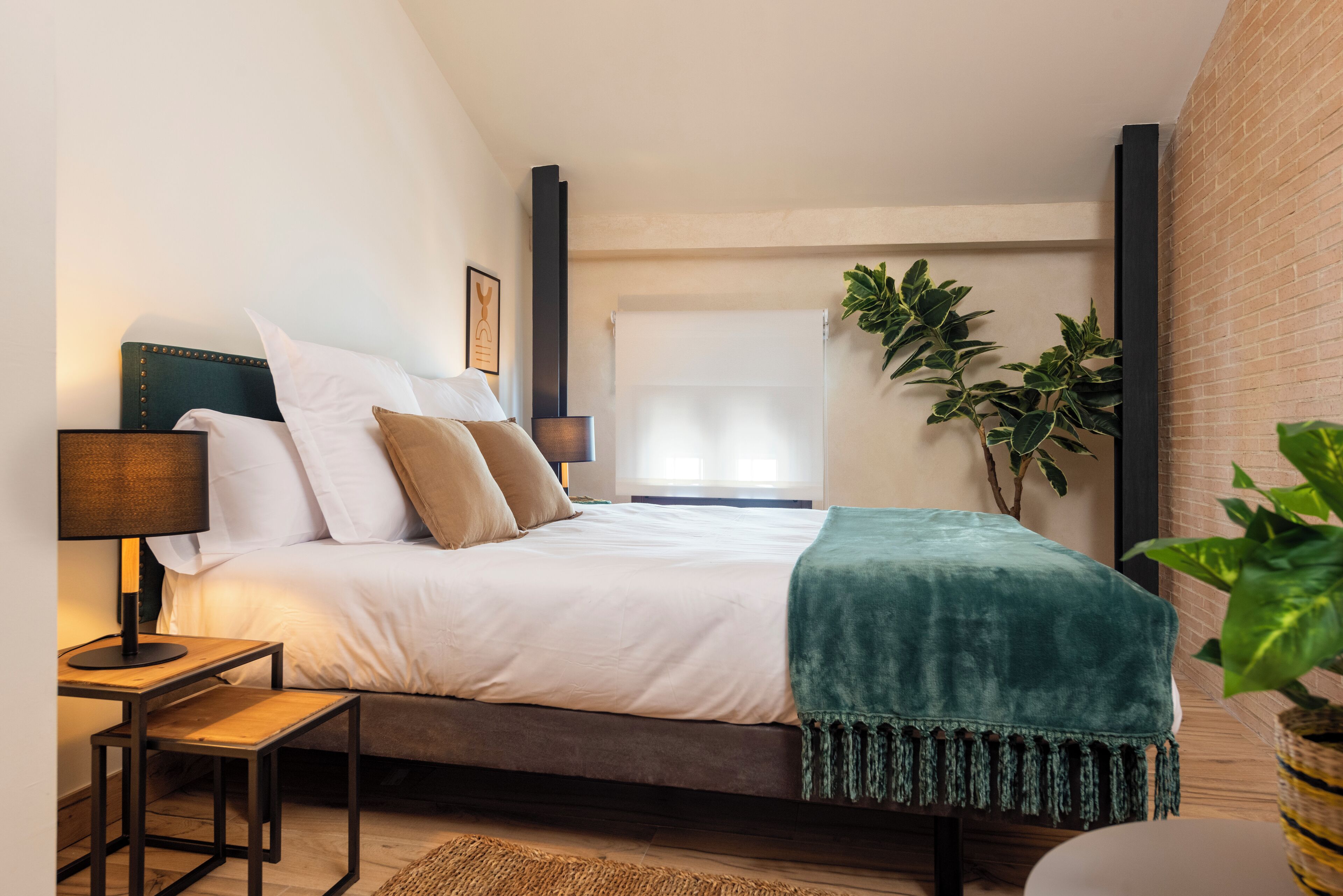 A modern bedroom with a bed, bedside tables, a lamp, and a large window with curtains.