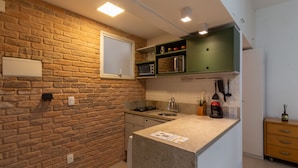 A kitchen with a stone backsplash, a built-in microwave, and a green upper cabinet. - 3 minutes from Ipanema beach | JN202 (Rio de Janeiro)